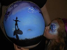 a pregnant woman with her belly painted to look like a man on top of a mushroom