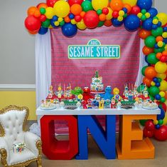 the sesame street birthday party is set up with balloons, cake and cupcakes