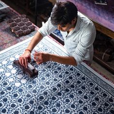 a man is working on an intricately designed rug