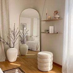 a mirror sitting on top of a wooden floor next to a white vase filled with flowers