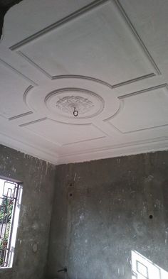 an unfinished room with concrete walls and ceiling tiles on the ceiling, along with a window