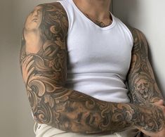 a man with tattoos is leaning against a wall