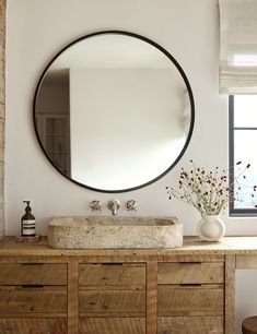 a bathroom vanity with a round mirror above it