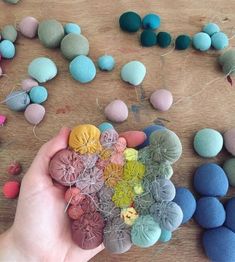 someone is holding up some colorful rocks on a table with string and yarn around them