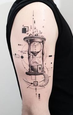 a man's arm with a clock and hourglass tattoo on the left shoulder