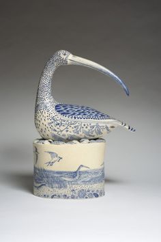 a blue and white bird figurine sitting on top of a cup with lid