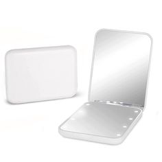 a white mirror sitting on top of a table next to a small square box with a lid