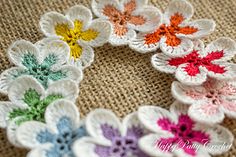 several crocheted flowers are arranged on a piece of burlocked fabric