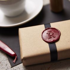 a waxed seal sits on top of a brown box next to a cup and saucer