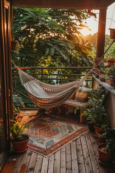 Cozy balcony with a hammock, patterned rug, and potted plants, overlooking a lush green forest at sunset. Earthy Balcony, Airbnb Furniture, City Balcony, Small Apartment Balcony Ideas, Apartment Balcony Ideas