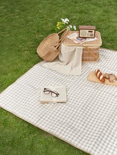 a picnic blanket with some food on it and a bag sitting next to it in the grass