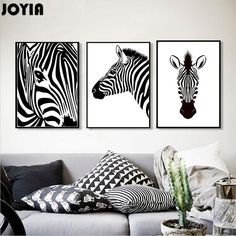 three black and white zebras are hanging on the wall above a couch in a living room