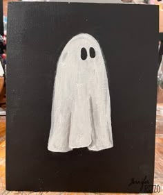 a painting of a ghost with two eyes on it's face, sitting on a table