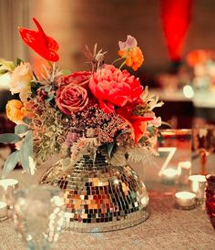 a vase filled with flowers sitting on top of a table next to glasses and candles