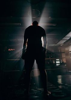 a man standing in the middle of a dark room with his back turned to the camera