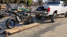 a white truck pulling a motorcycle behind it