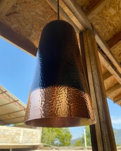 a close up of a metal object hanging from a wooden ceiling over a parking lot