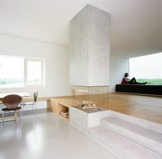 a person sitting on a bench in a room with white walls and wood flooring