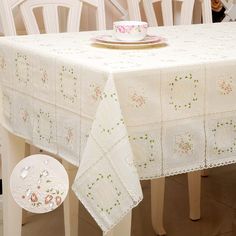 a white table cloth with pink flowers on it and a tea cup sitting on top