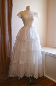 a white dress sitting on top of a mannequin in front of a window