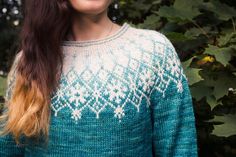 a woman with long brown hair wearing a blue and white sweater smiling at the camera