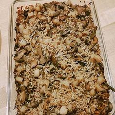 a casserole dish filled with rice and nuts on top of a wooden table