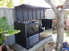 an air conditioner sitting in the middle of a yard next to a tree and potted plant