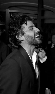 a black and white photo of a man in a tuxedo with his mouth open