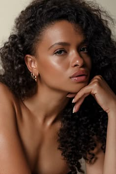 a close up of a woman with curly hair wearing gold earrings and looking off to the side