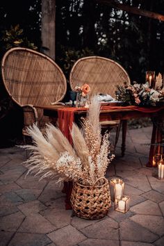 two wicker chairs sitting next to a table with flowers and candles