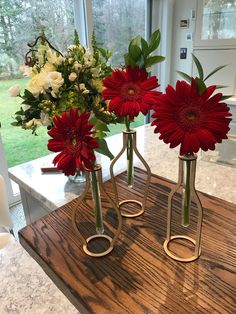 three vases with flowers in them sitting on a table