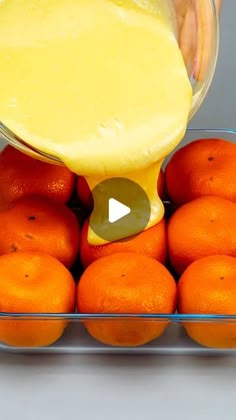 someone pouring orange juice into a container filled with oranges