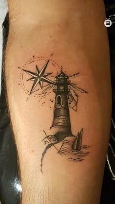 a man's leg with a lighthouse and sailboat tattoo on the side of his calf