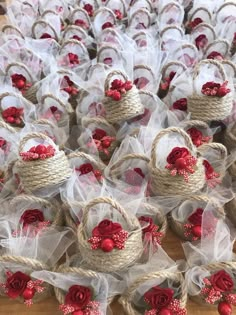 several baskets with red flowers and burlocks tied to them on a wooden table