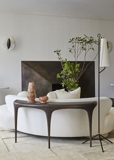 a living room filled with furniture and a plant on top of a table in front of a painting