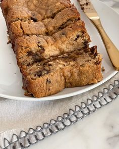 slices of chocolate chip banana bread on a white plate next to a fork and spoon