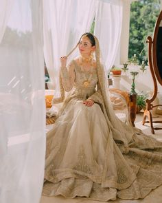 a woman sitting on top of a bed wearing a wedding dress and jewelry in front of a mirror