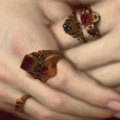 the woman is wearing several rings on her hands, including one with a red stone