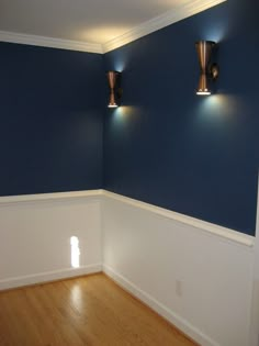 an empty room with two lights on the wall and hard wood floors in front of it