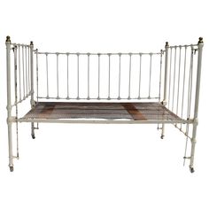 a white metal bed frame sitting on top of a checkered blanket covered floor next to a wall