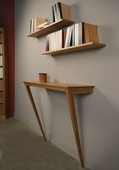 two wooden shelves with books on them against a wall