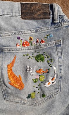 a pair of jeans with embroidered fish and flowers on them