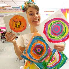 a woman is holding up some art work