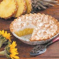 a pie sitting on top of a wooden table next to sunflowers and pine cones