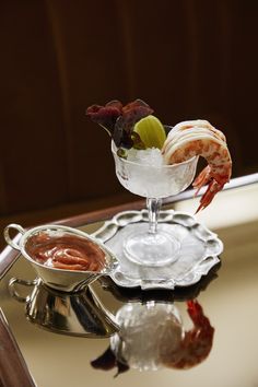 a shrimp cocktail with garnishes and sauces on a silver platter