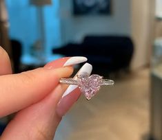 a woman's hand holding a ring with a heart shaped diamond on the side