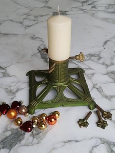 a candle is sitting on top of a small stand with ornaments around it in gold, red and green