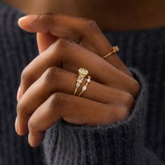 a close up of a person's hands holding two rings with diamonds on them