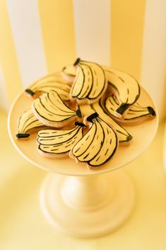 cookies decorated with bananas are on a white plate in front of a striped wall and yellow tablecloth