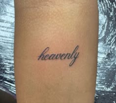 a woman's leg with the word heavenly tattooed on it, in cursive font